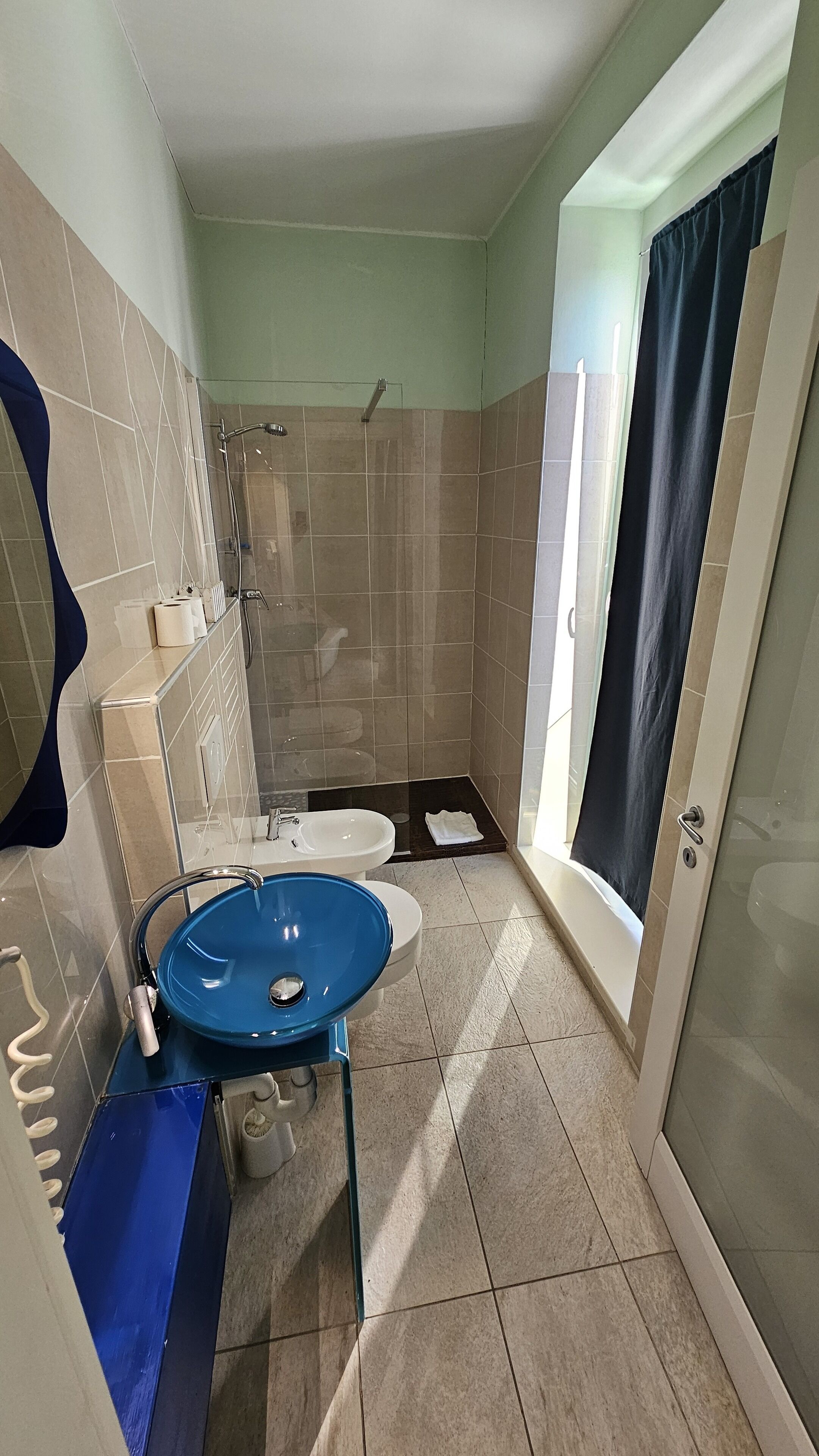 Un baño con un lavabo azul, ducha e inodoro.