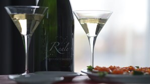 Two martini glasses and a bottle of wine on a table with a plate of caviar. - Notte Stellata (Savigliano)
