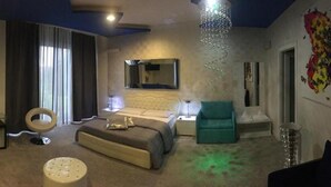 A bedroom with a bed, a sofa, a chair, a small table, and a decorative wall piece. - Notte Stellata (Savigliano)