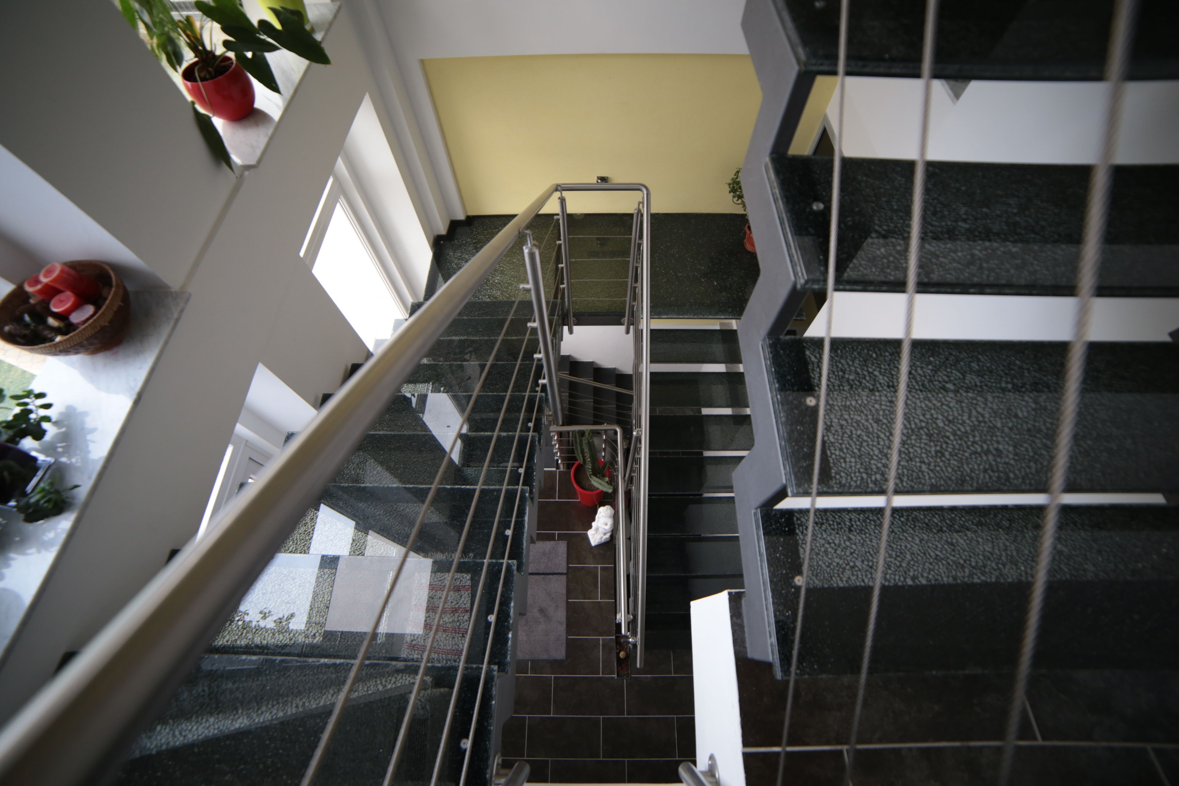 Eine Treppe mit Metallgeländern, einem Blumentopf und einem roten Eimer auf der Zwischenebene.
