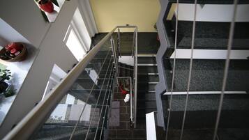 Eine Treppe mit Metallgeländern, einem Blumentopf und einem roten Eimer auf der Zwischenebene.