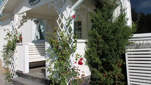 A white building with a sign reading "Rosen" and a wooden porch with steps. - Skotteks Gården (Ulricehamn)