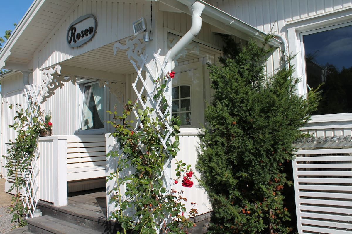 A white building with a sign reading "Rosen" and a wooden porch with steps.