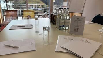 A hotel desk with a view of mountains, a pen, papers, and water bottles.