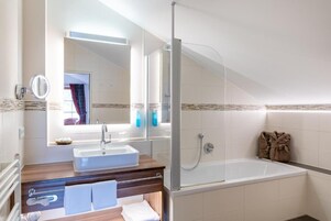 Un baño moderno con ducha envuelta en vidrio, lavamanos y bañera.
