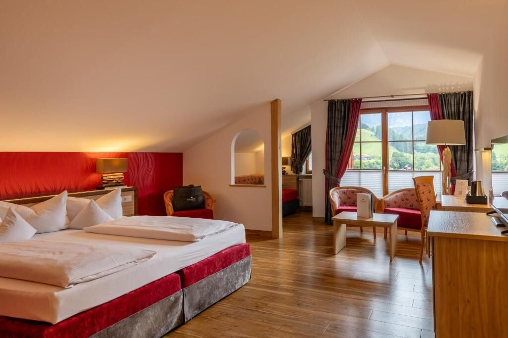 A hotel room with a bed, a desk, a chair, and a view of the outdoors.