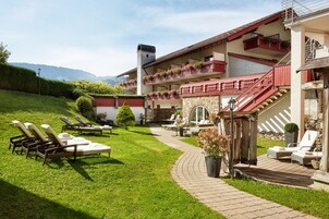 Un hotel con terraza al aire libre, fachada de piedra y vistas a la montaña.