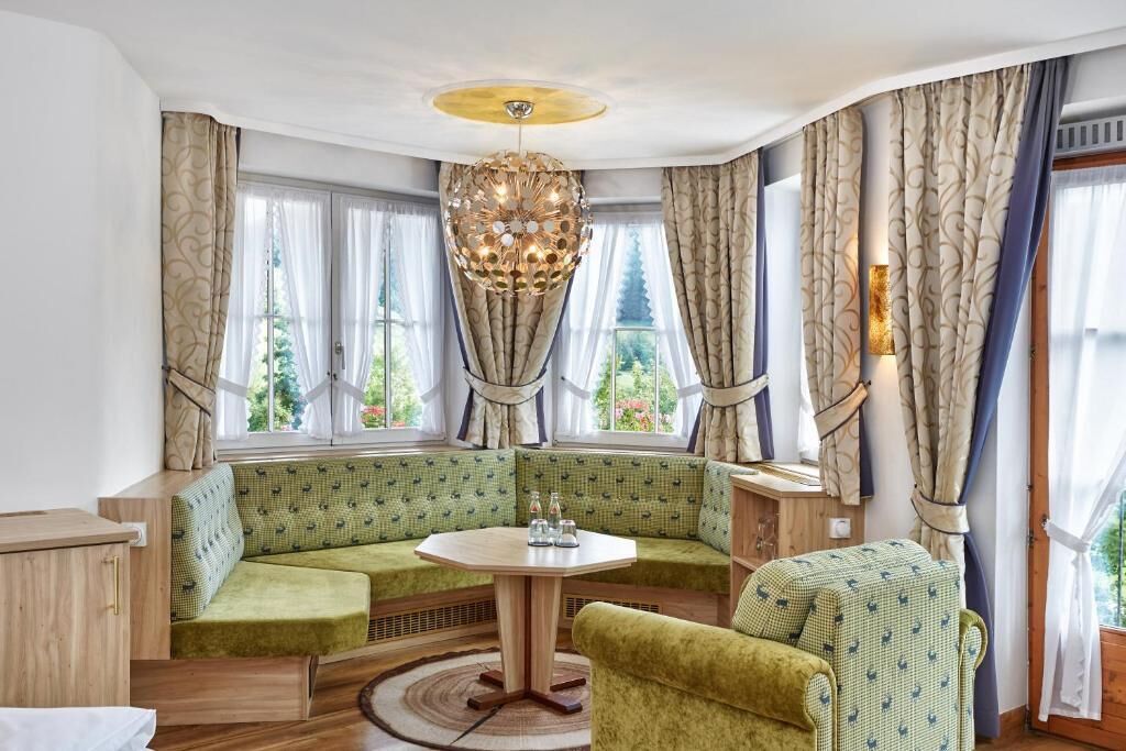 Une pièce chaleureuse avec un canapé vert, une table ronde et un lustre.