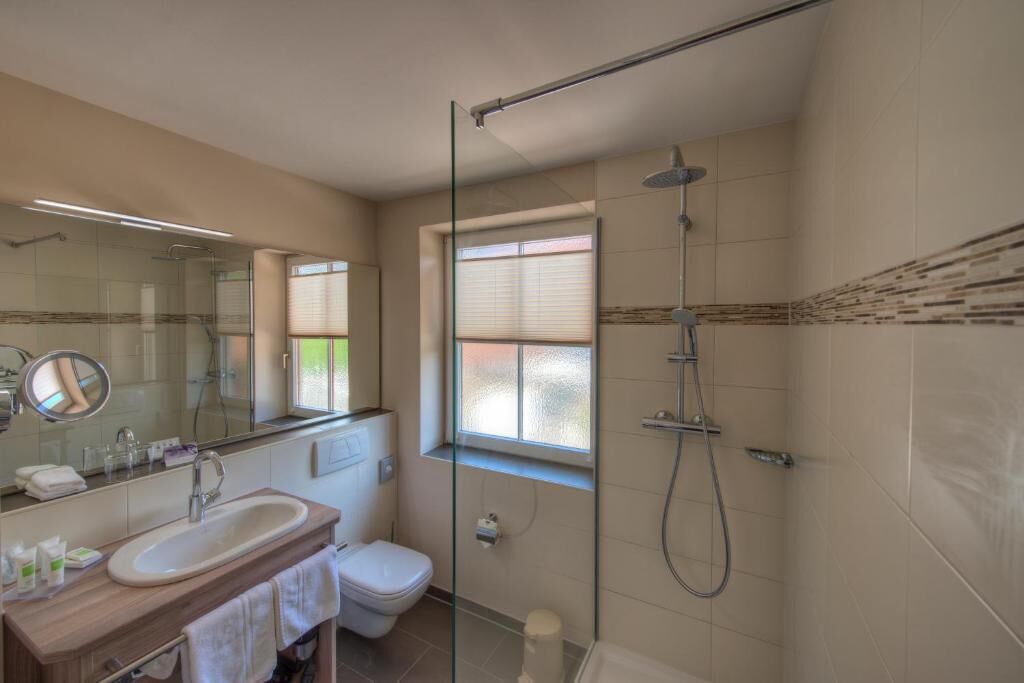 Un baño moderno con ducha de vidrio, lavamanos, inodoro y ventana.