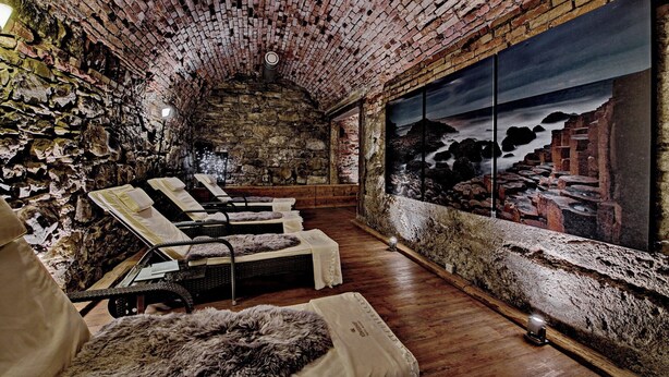 A stone-walled room with a large window, wooden flooring, and several reclining chairs. - Königshof Hotel Resort- Partner von Oberstaufen PLUS und PLUS GOLF (Oberstaufen)