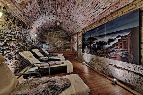 A stone-walled room with a large window, wooden flooring, and several reclining chairs.