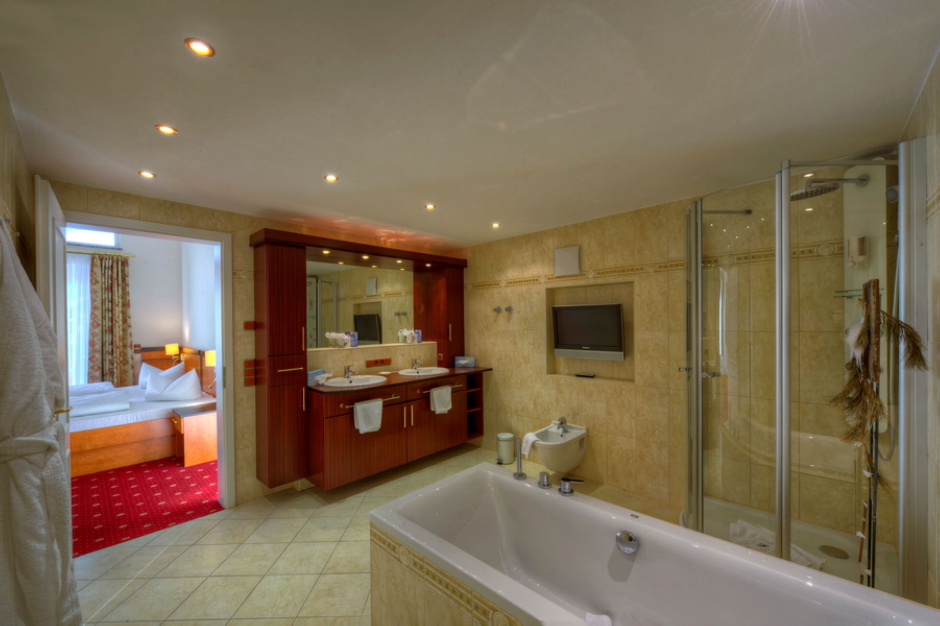 A hotel bathroom with a large bathtub, a shower, and a double sink vanity.