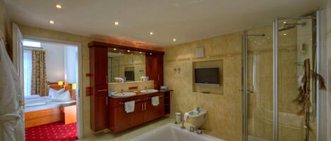 A hotel bathroom with a large bathtub, a shower, and a double sink vanity.