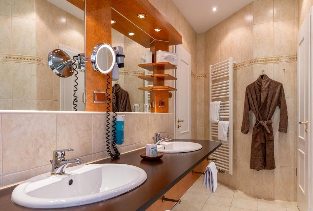Une salle de bain avec deux lavabos, un miroir, un porte-serviettes et un peignoir accroché au mur.