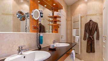 Une salle de bain avec deux lavabos, un miroir, un porte-serviettes et un peignoir accroché au mur.
