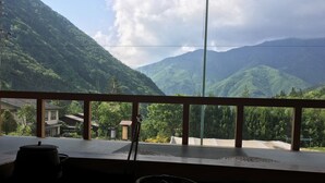 A room with a view of mountains, a wooden railing, and a sandy floor. - Ryokan Sansui (Takayama)