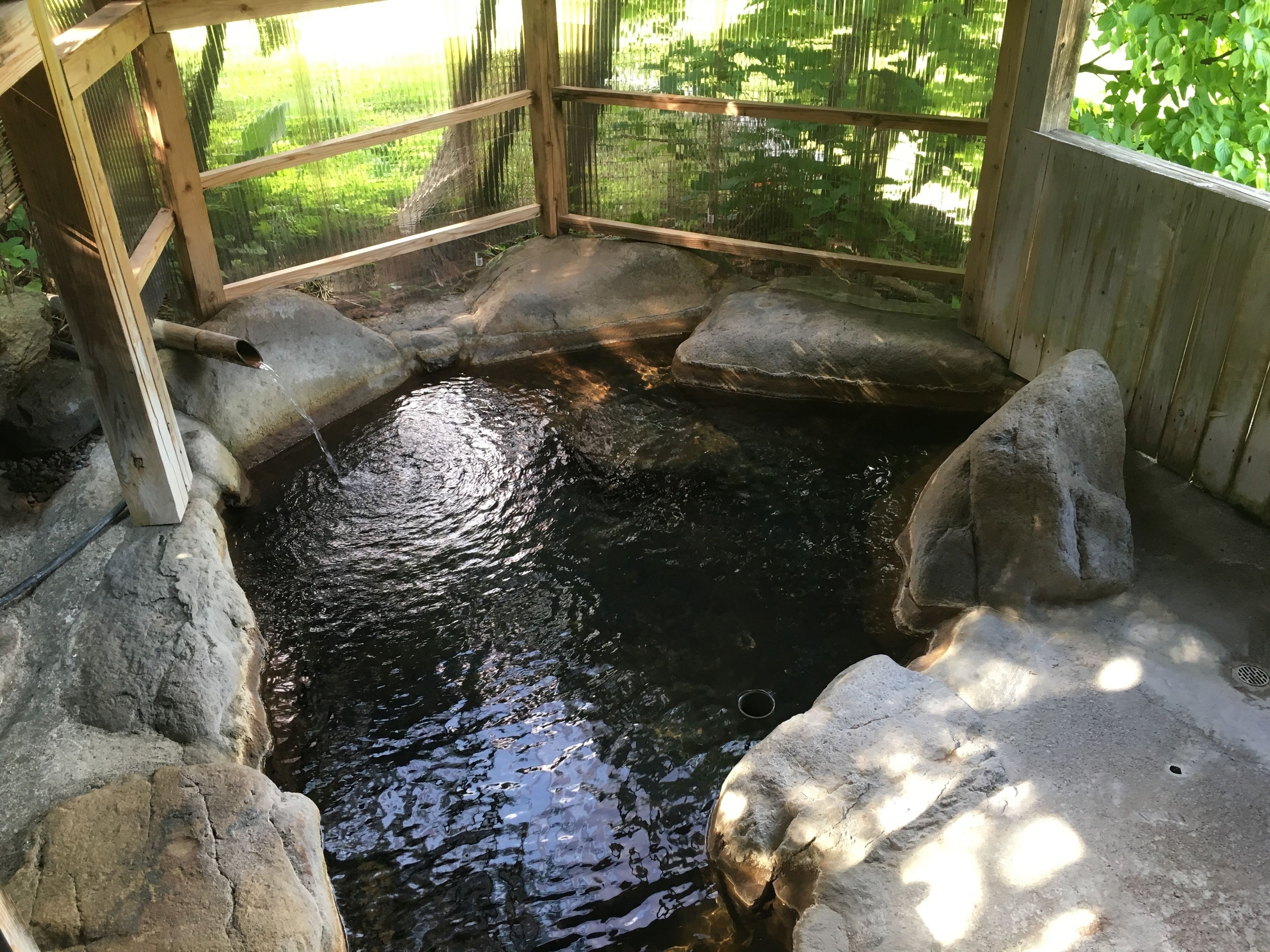 A small, enclosed pond with a wooden structure and rocks around it.