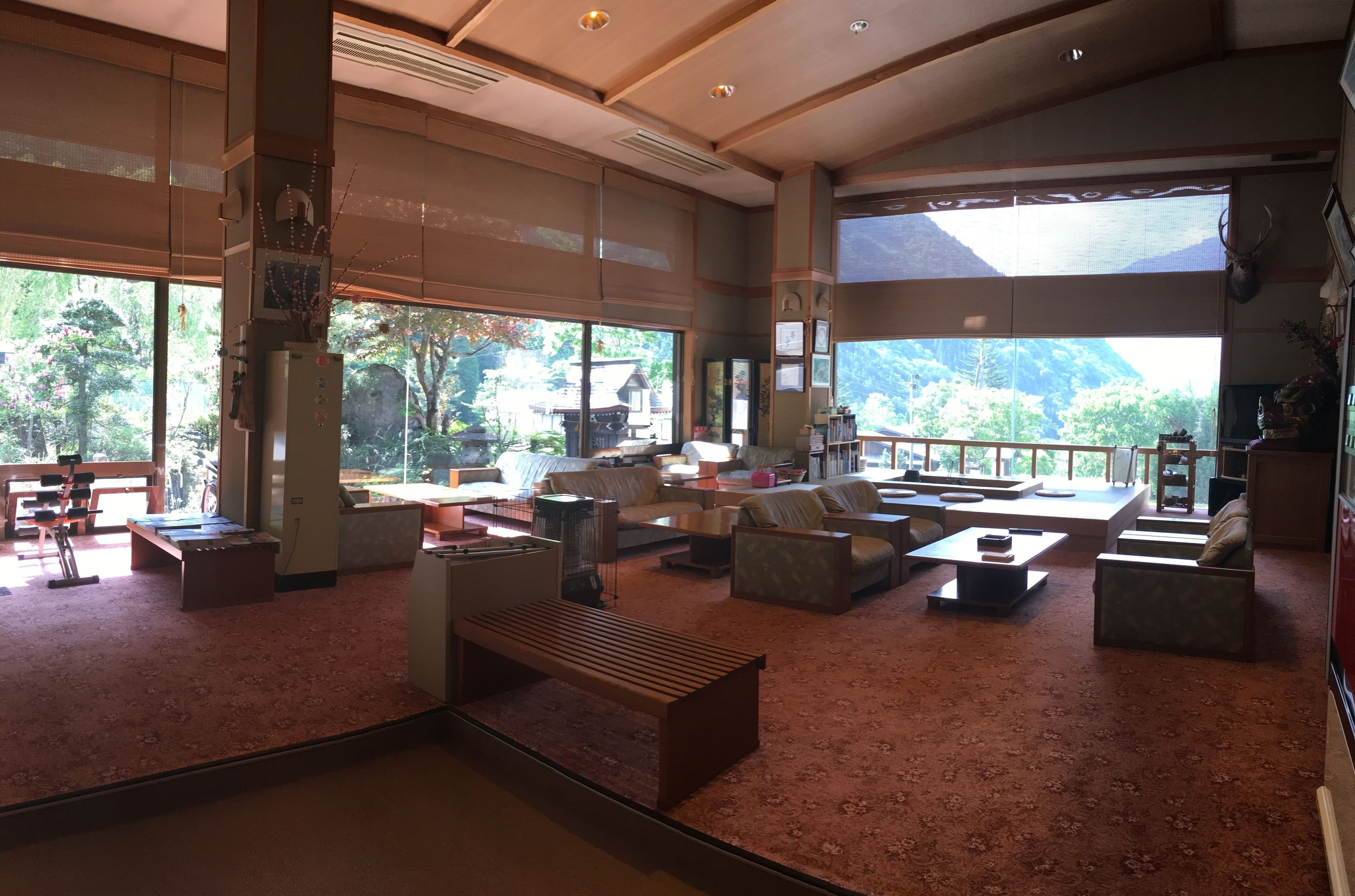 A spacious living room with large windows, a wooden bench, and a variety of seating options.