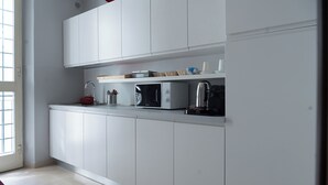 Una cocina moderna con armarios blancos, un microondas y un hervidor en la encimera.