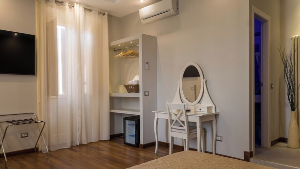 Un dormitorio con cama, escritorio con espejo, armario y aire acondicionado.