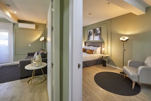 Una moderna camera d'hotel con un letto, una poltrona, un tavolino e una lampada da terra.
