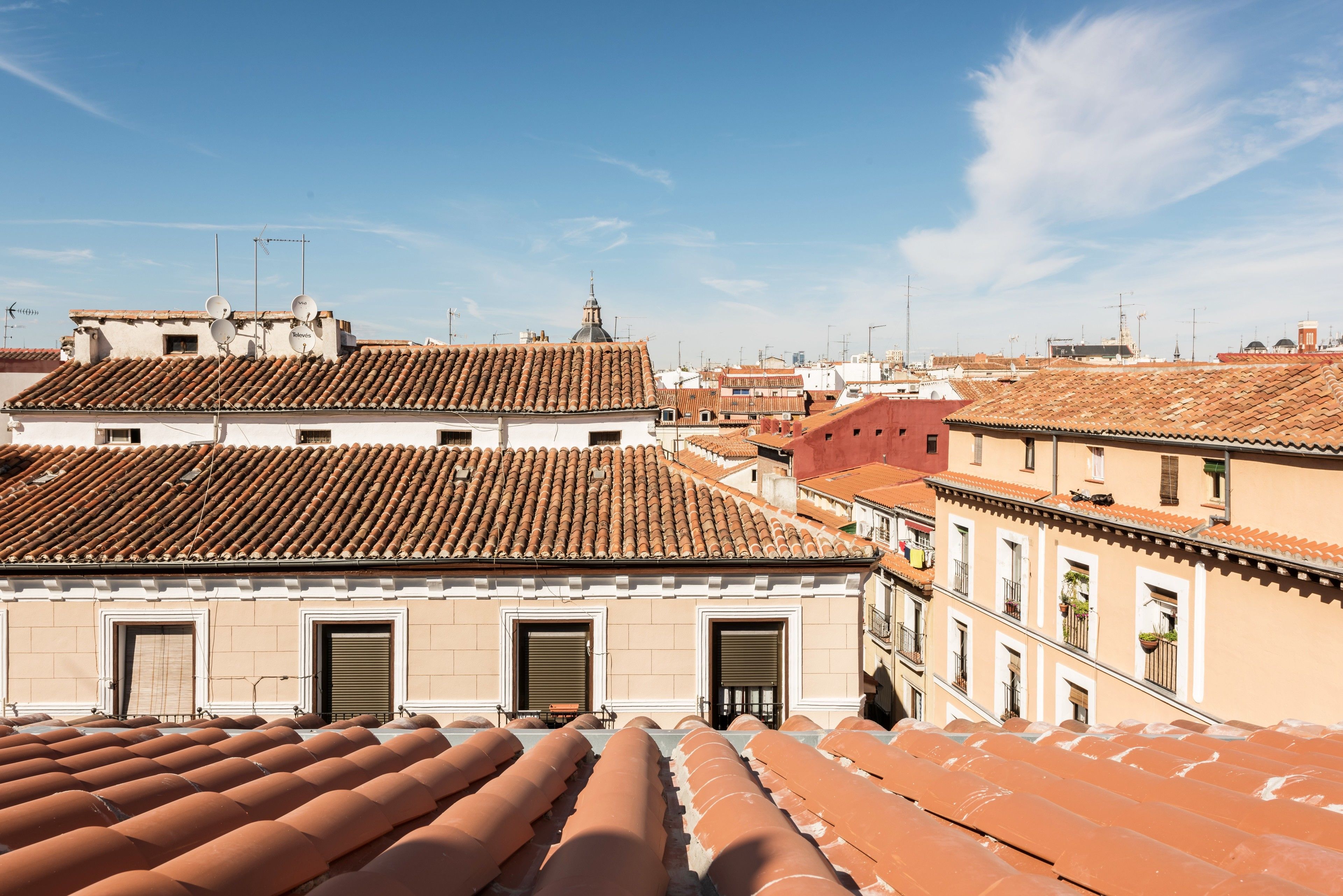 Vista de tejados de tejas color terracota y edificios con numerosas ventanas y balcones.
