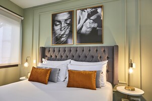 A neatly made bed with white and brown pillows, a tufted headboard, and two bedside tables with lamps.
