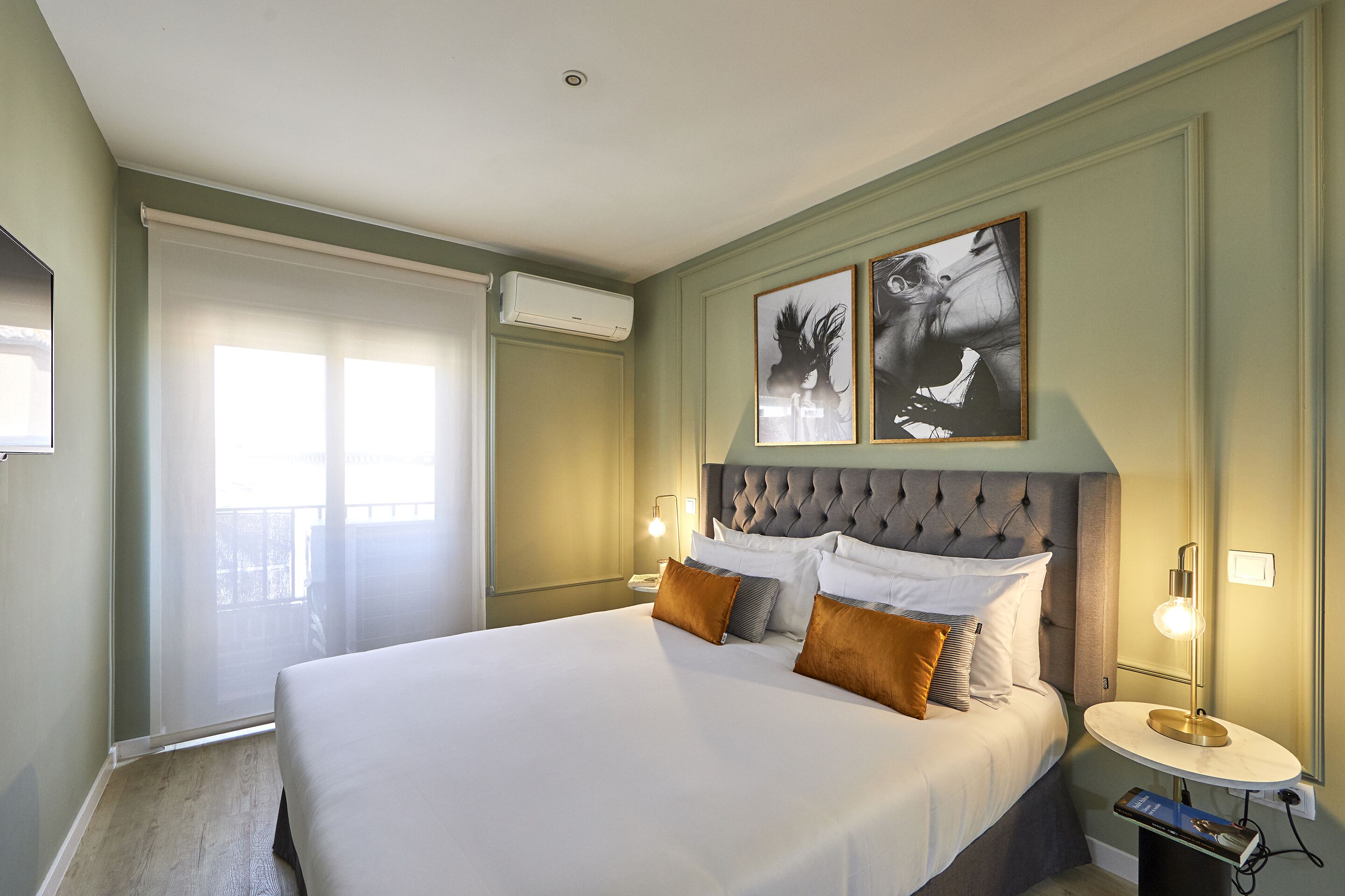 Een keurig opgemaakte hotelkamer met een groot bed, een nachtkastje met een lamp en kunst aan de muur.