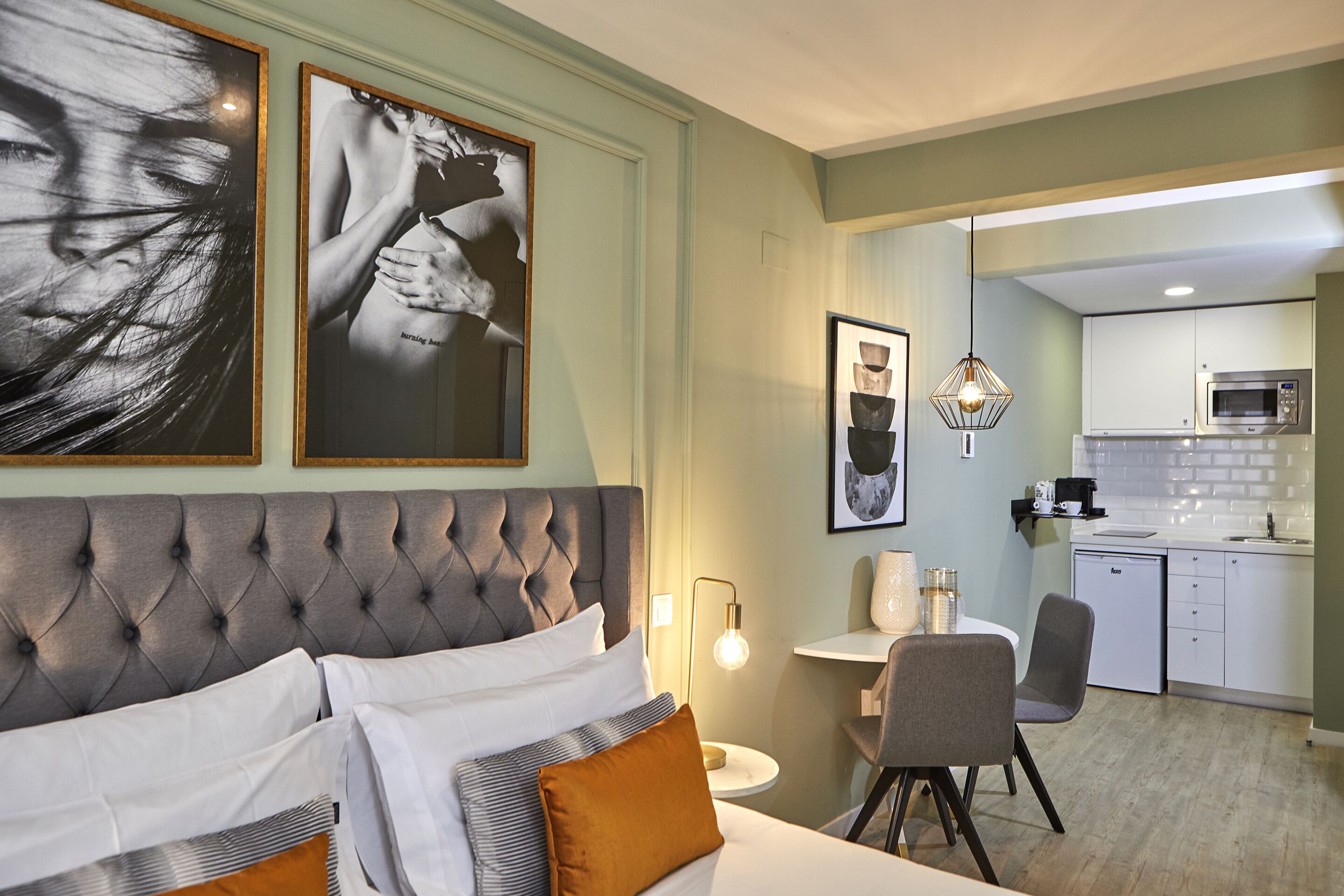 A hotel room with a large bed, a dining area, and a kitchenette.