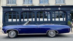 Une voiture décapotable bleue, modèle classique, est garée devant l’hôtel La Marine de Loire.