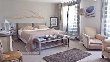 A modern bedroom with a bed, bedside table, lamp, chair, and a view of the outdoors.