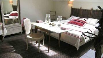 A bedroom with a bed, a chair, a table, and a mirror.
