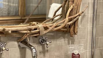 Un baño con lavamanos de mármol, ramas de madera y un perchero para toallas.