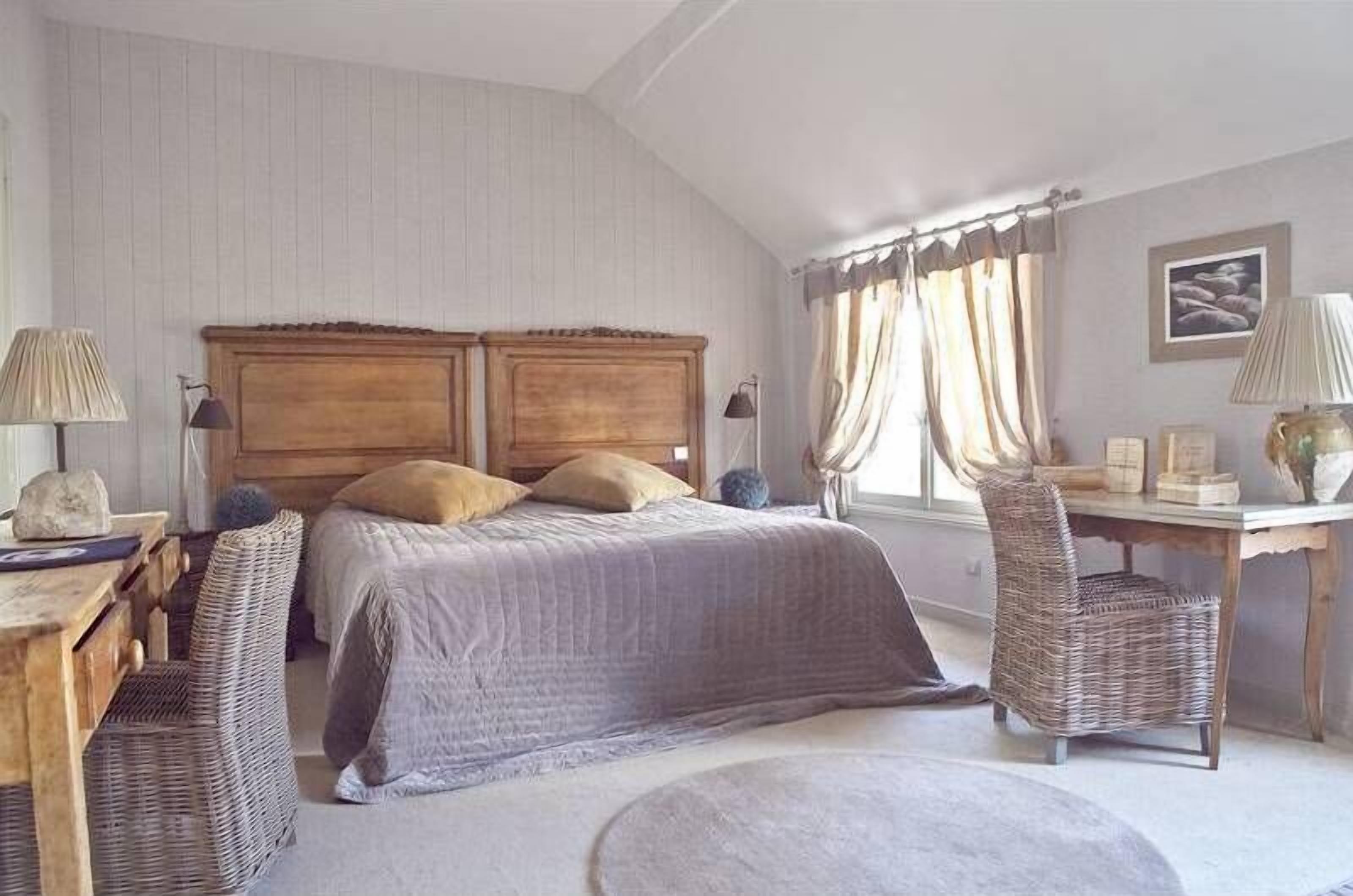 Un dormitorio con una cama grande, dos mesitas de noche, un escritorio y una silla.