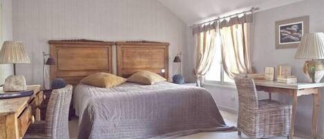Un dormitorio con una cama grande, dos mesitas de noche, un escritorio y una silla.