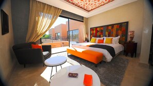 Ein modernes Hotelzimmer mit einem großen Bett, einer Couch, einem runden Tisch und einem Balkon mit Vorhängen.