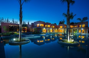 A modern hotel with a pool area, multiple buildings, and palm trees.
