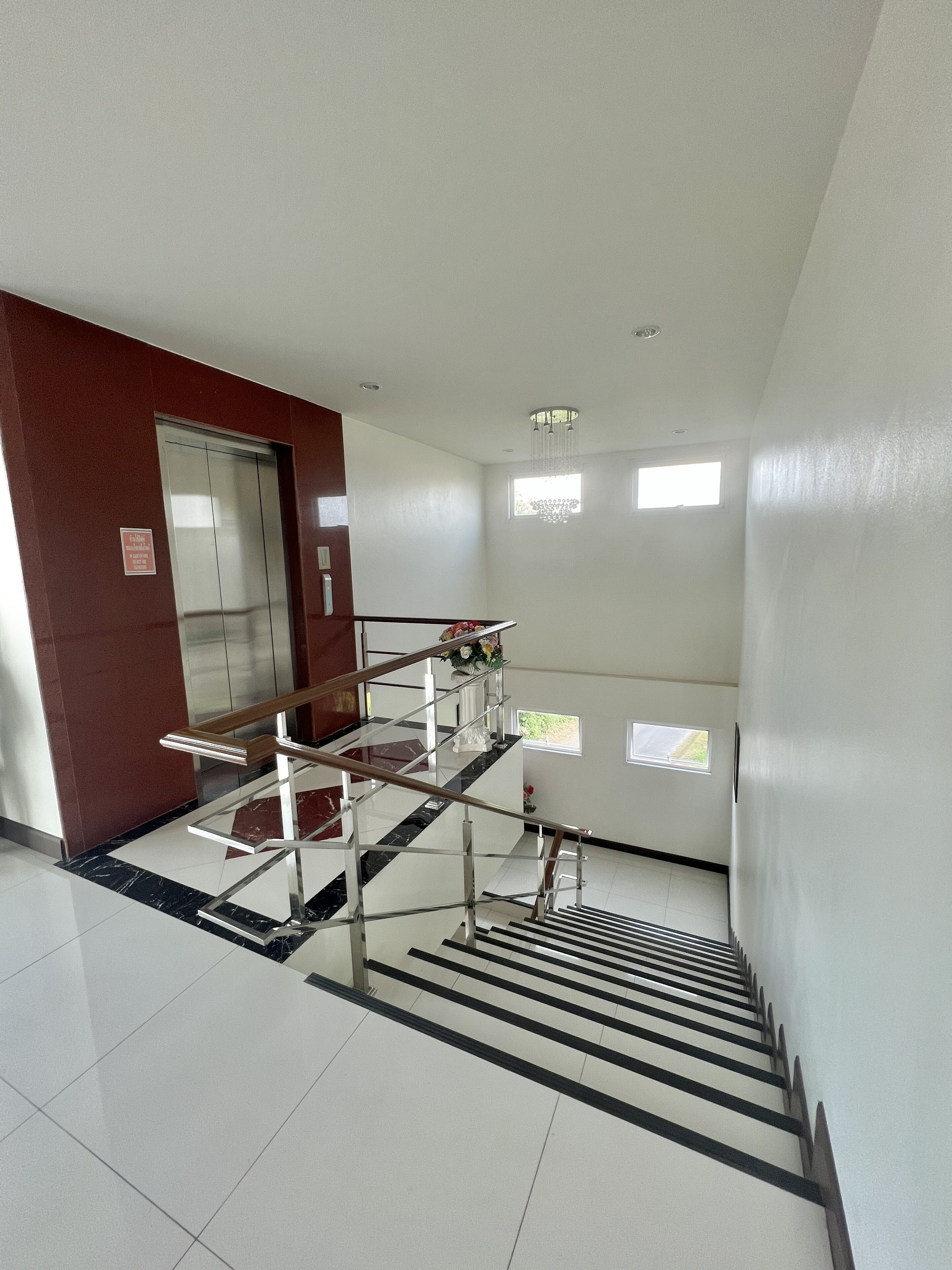 A modern interior with a staircase, elevator, and a red accent wall.