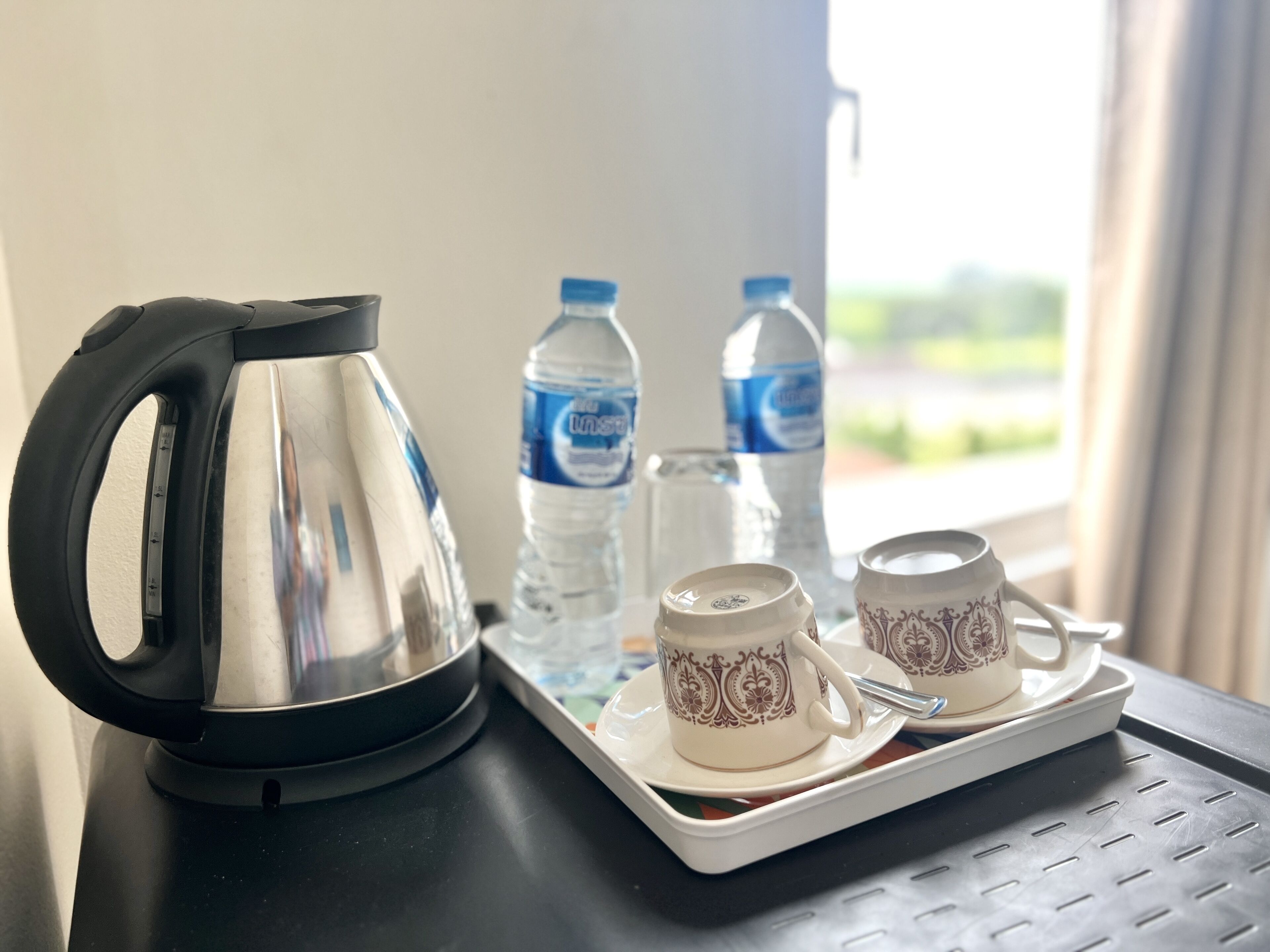 Una tetera, dos tazas y dos botellas de agua sobre una bandeja.