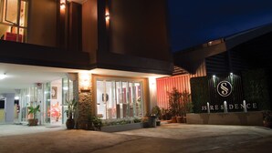 A modern building with a well-lit entrance, a visible address sign, and a landscaped area with potted plants. - JS Residence Krabi (Krabi)