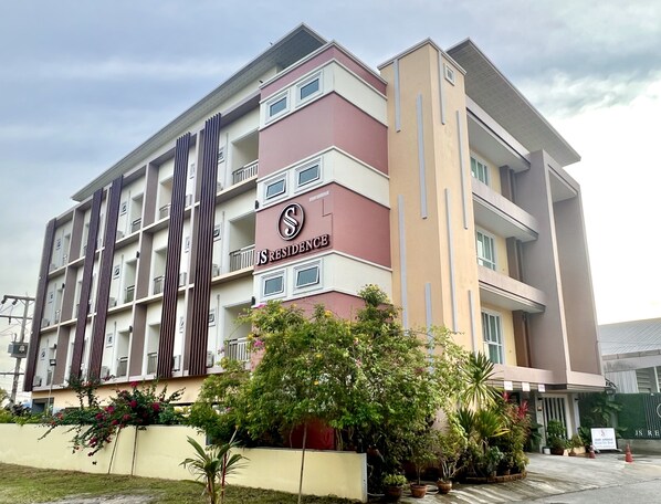 A multi-story residential building with balconies, a sign reading "JS Residence," and a landscaped garden area with potted plants. - JS Residence Krabi (Krabi)