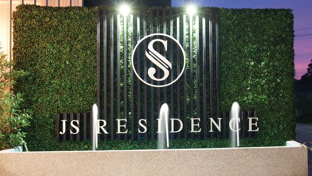 A landscaped entrance with a hedge, a fountain, and the text "JS RESIDENCE". - JS Residence Krabi (Krabi)