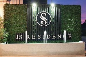 A landscaped entrance with a hedge, a fountain, and the text "JS RESIDENCE". - JS Residence Krabi (Krabi)