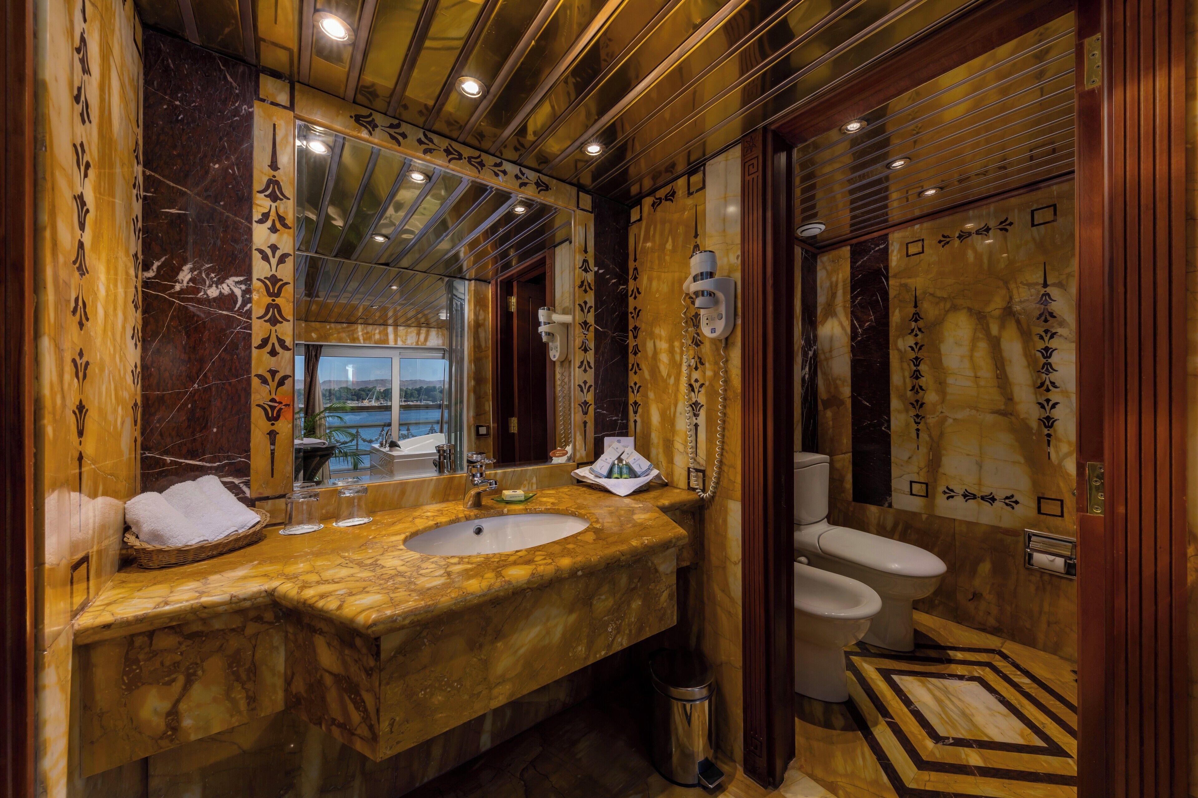 Une salle de bain luxueuse avec un lavabo en marbre, un grand miroir et des toilettes.