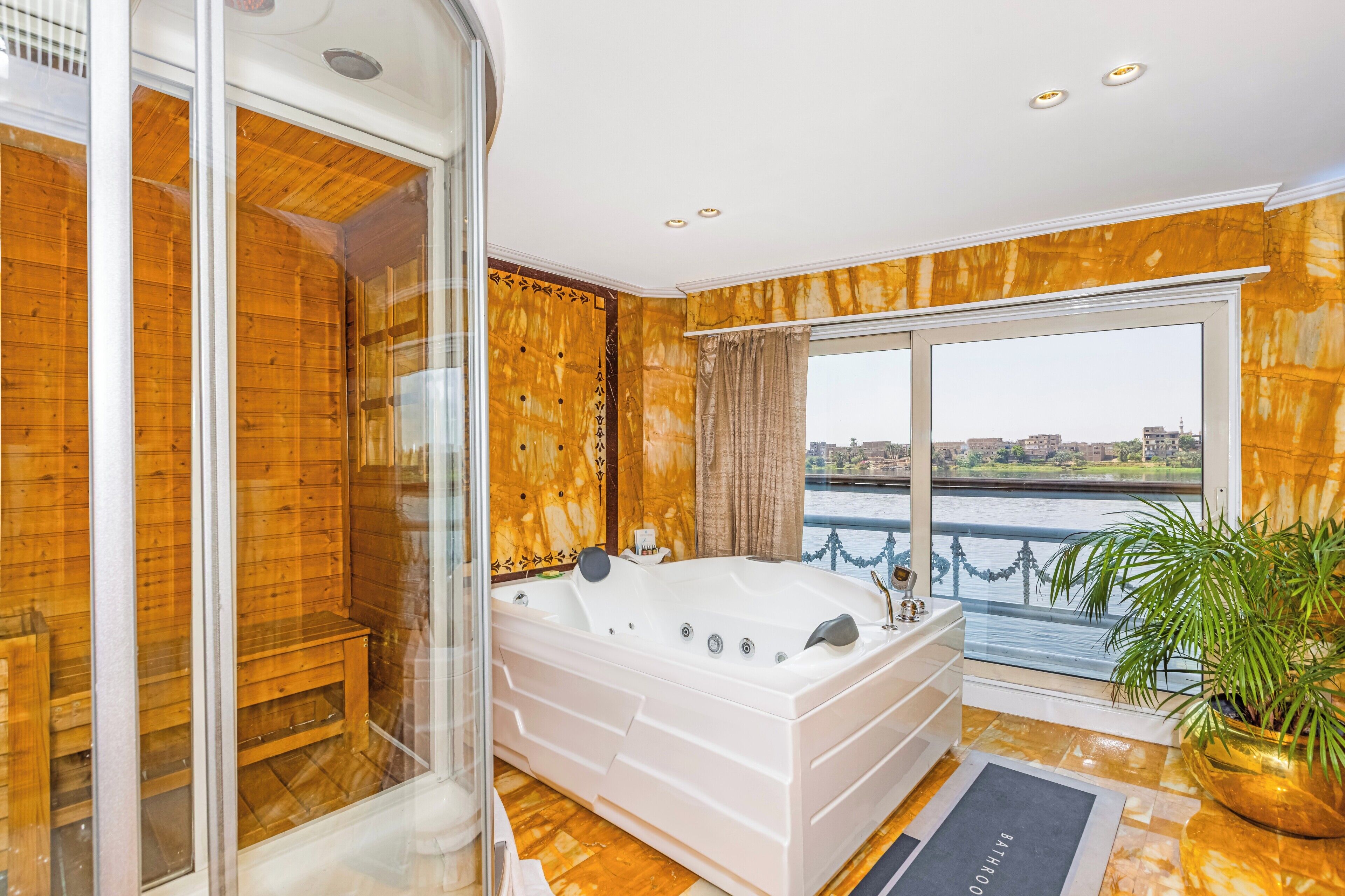 Un baño moderno con una bañera grande, mampara de cristal y vistas a un río.