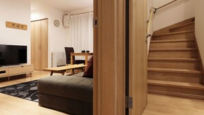 Ein modernes Wohnzimmer mit Holzboden, einer Couch, einem Fernseher und einer Treppe.