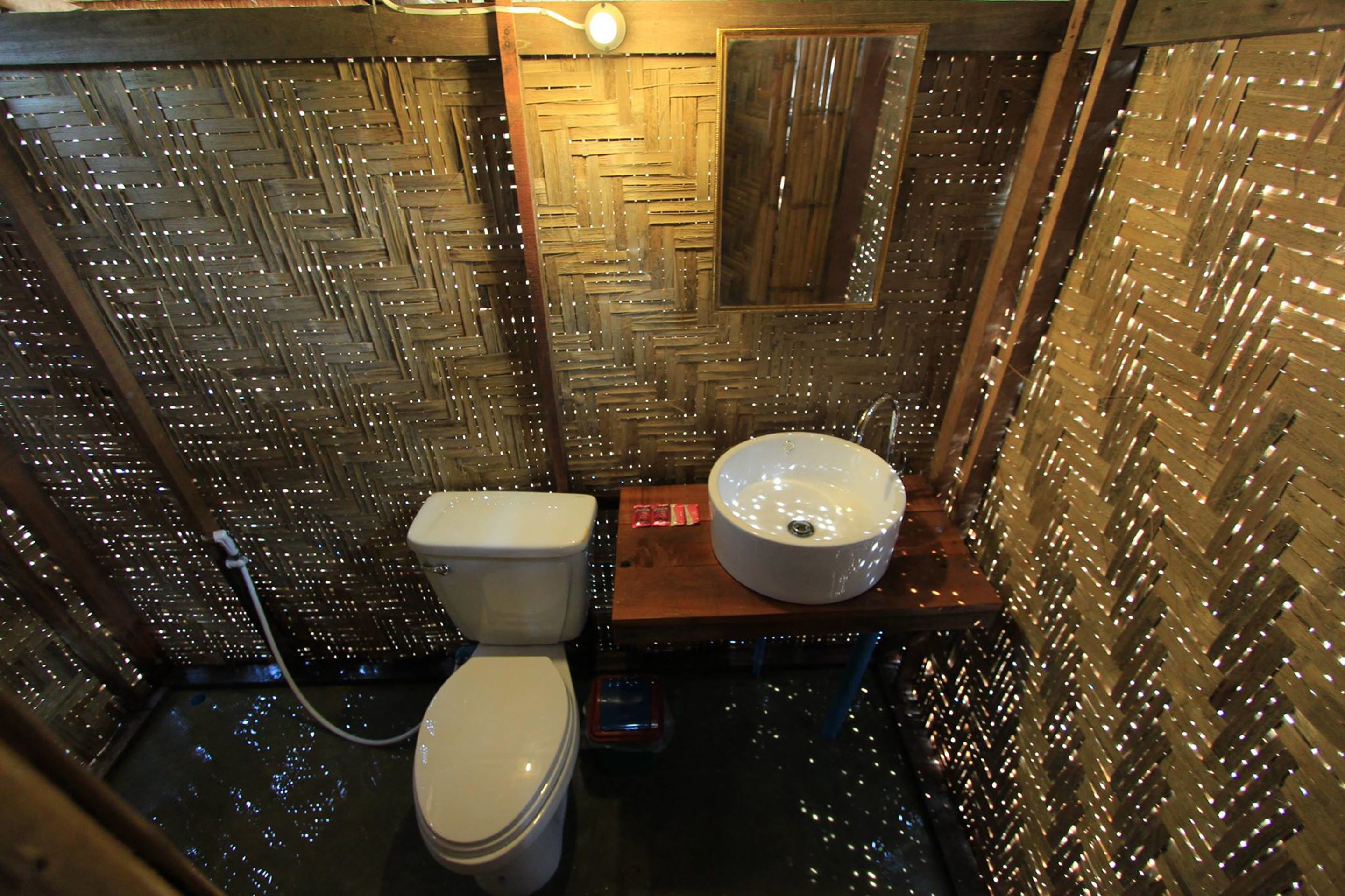 Une salle de bain avec un motif mural tissé, des toilettes blanches et un lavabo rond.