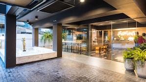 A modern lobby with a marble fountain, glass walls, and indoor plants. - Fyn Hotel (Bangkok)