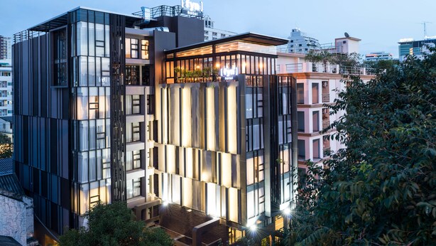 A modern hotel with a glass facade, multiple balconies, and a rooftop terrace. - Fyn Hotel (Bangkok)