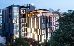 A modern hotel with a glass facade, multiple balconies, and a rooftop terrace. - Fyn Hotel (Bangkok)